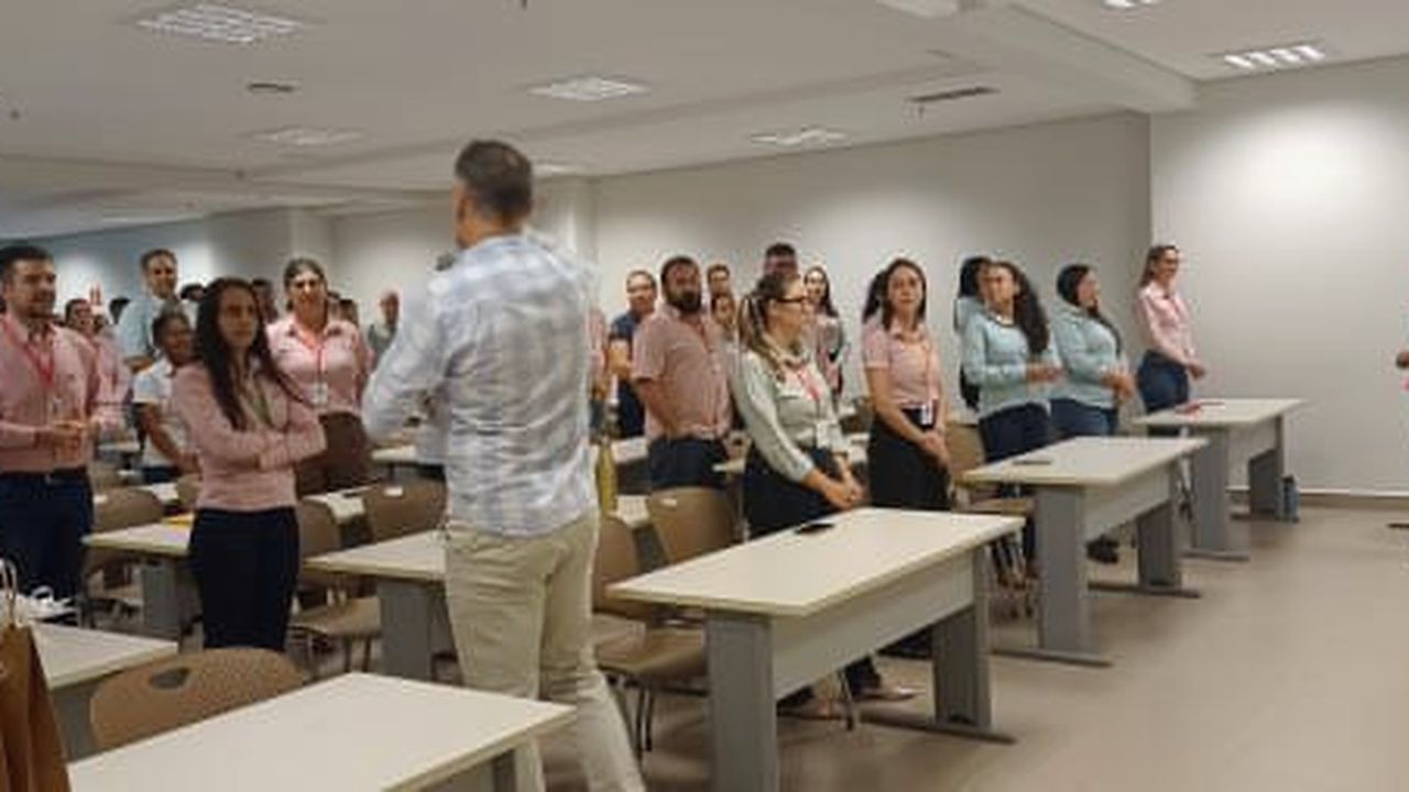 Dinâmica de comportamento seguro com equipe em pé durante palestra corporativa