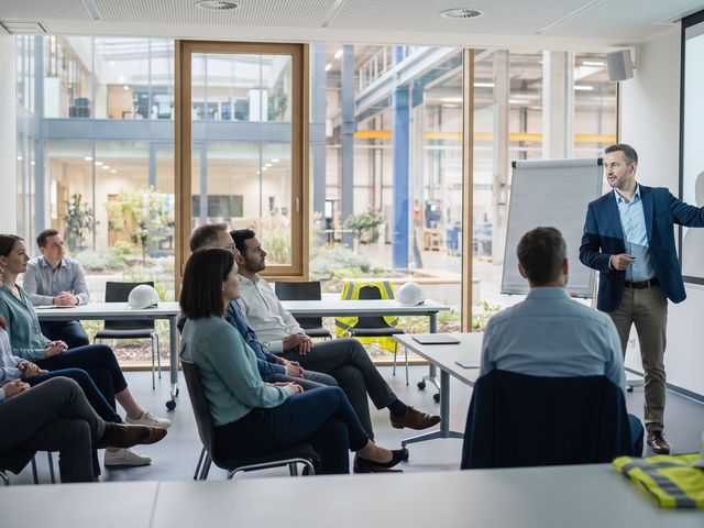 Colaboradores atentos em sessao de seguranca do trabalho em ambiente industrial moderno