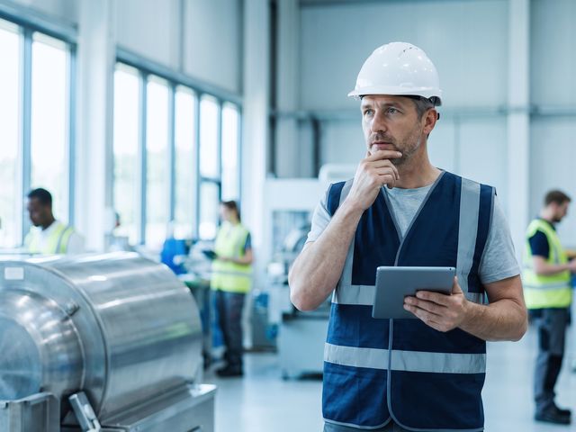 Profissional em ambiente industrial avaliando o entorno antes de uma tarefa